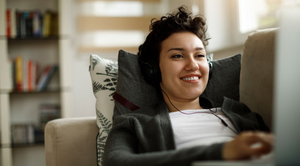 junge Frau auf Sofa spielt Pokemon auf Facebook