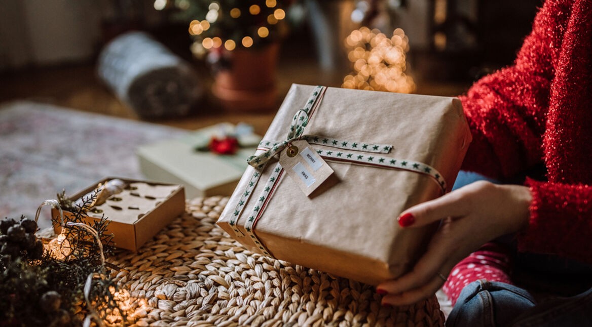Frau verschenkt Päckchen, in dem smarter Schmuck eingepackt ist.