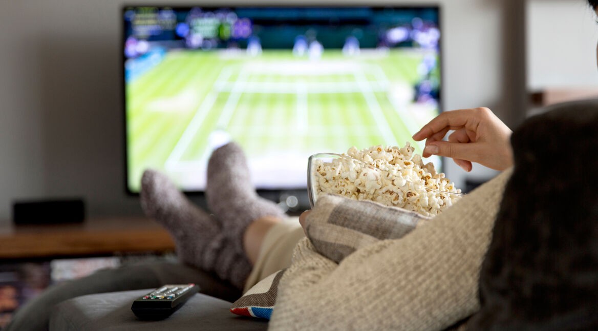 Frau isst Popcorn und sieht Fernsehen