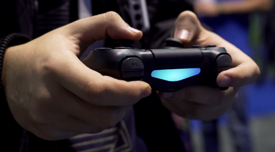 Mann spielt mit einem PS4-Controller ein Spiel.