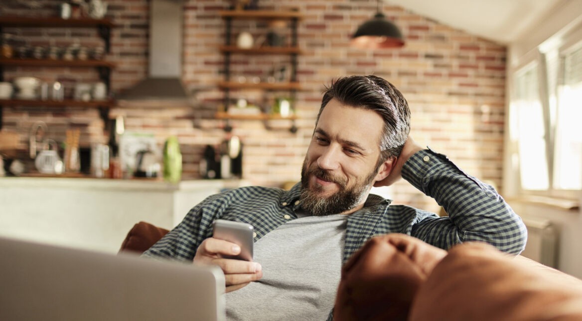 Mann mit Smartphone im Wohnzimmer