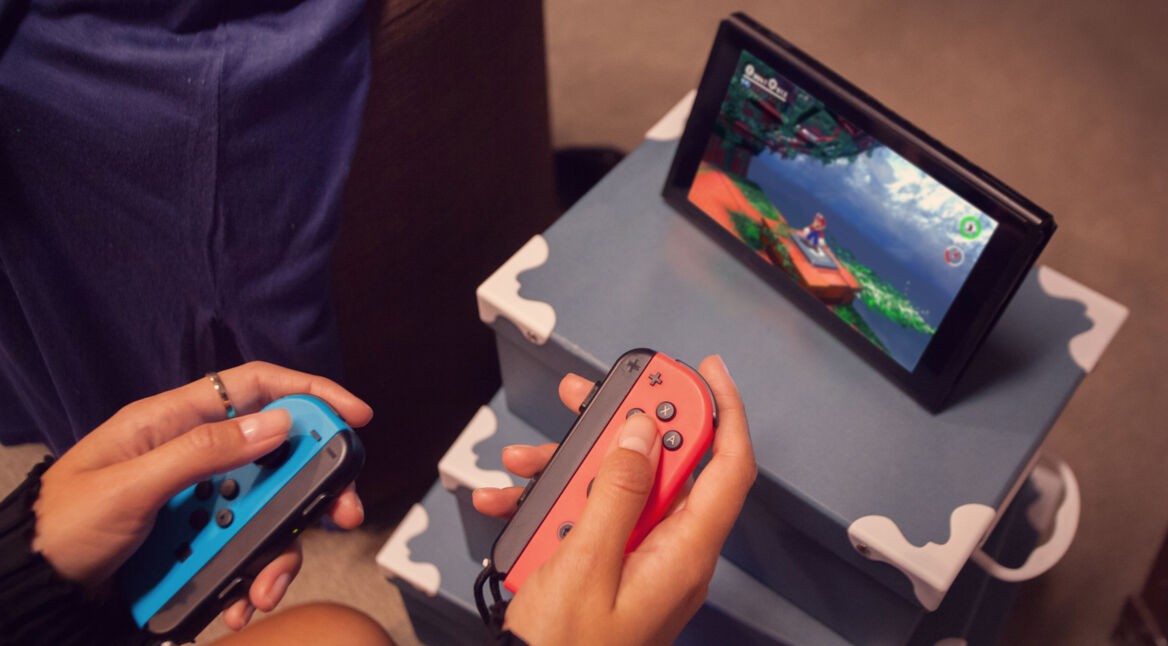 Eine junge Frau spielt mit den Joy-Con ein Game auf der Nintendo Switch.