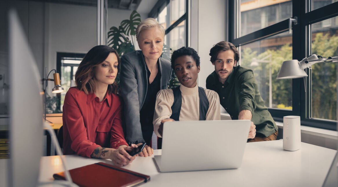Eine Gruppe Personen arbeitet gemeinsam an einem Laptop