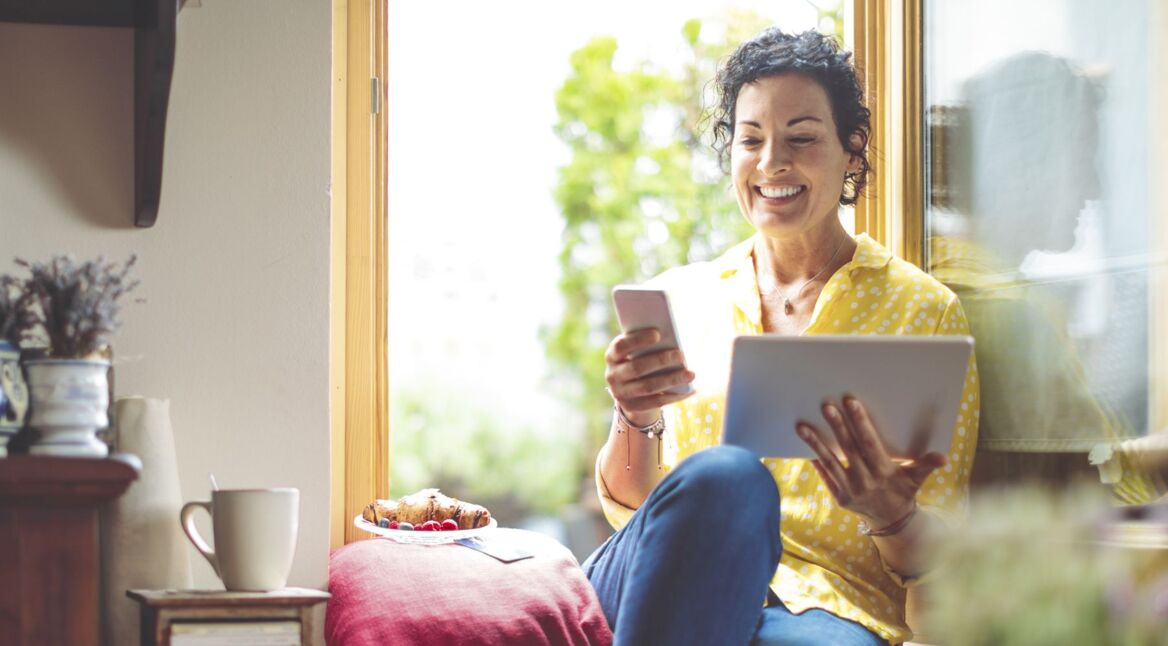 Frau nutzt WhatsApp auf Smartphone und Tablet.