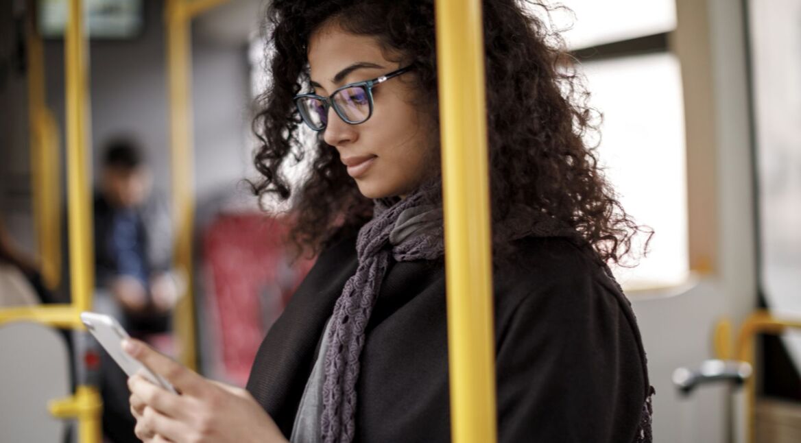 Frau sieht sich am iPhone den Dark Mode von Facebook an.