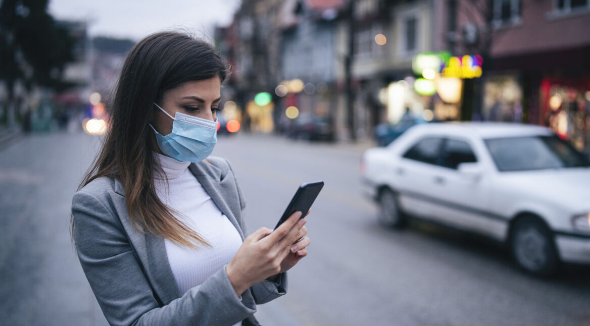 Frau mit Smartphone und Maske