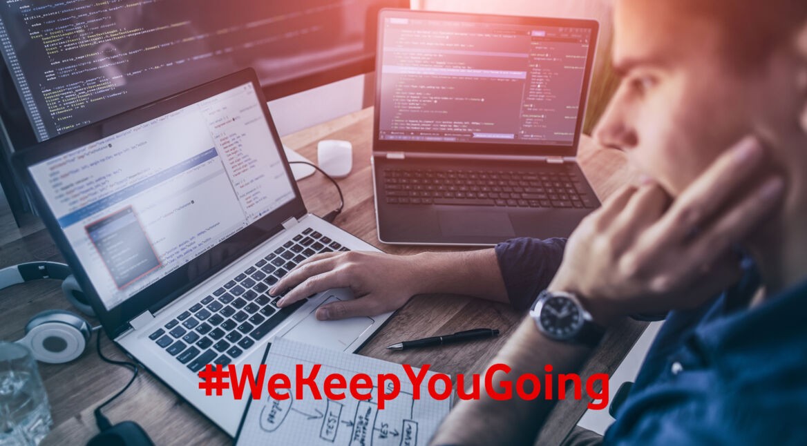 Ein Mann programmiert am Laptop und mit mehreren Bildschirmen.