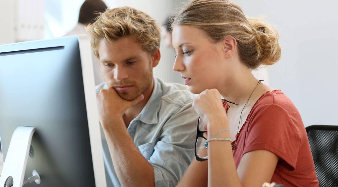 Media-Experten beraten sich vor Monitor über Video-Layout