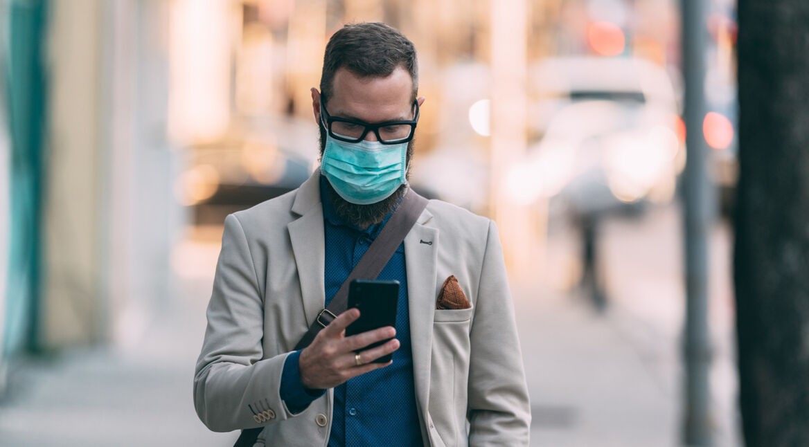 Mann mit Smartphone und Corona-Maske