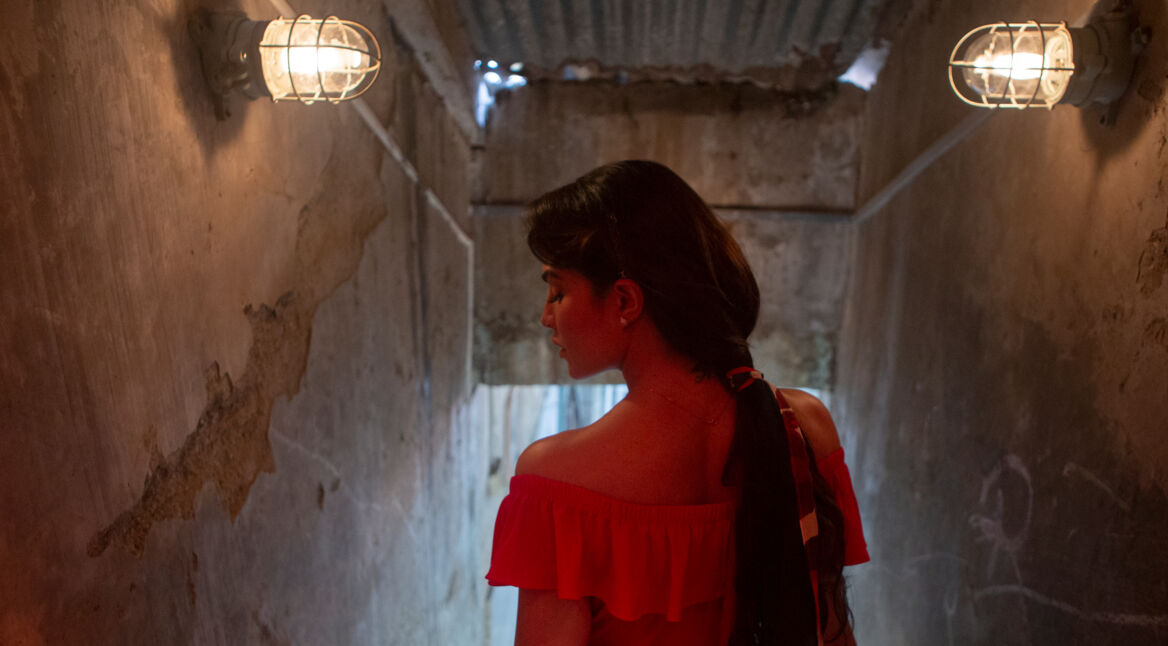 Sona steht in einem roten Kleid in "Mrs. Serial Killer im Flur"