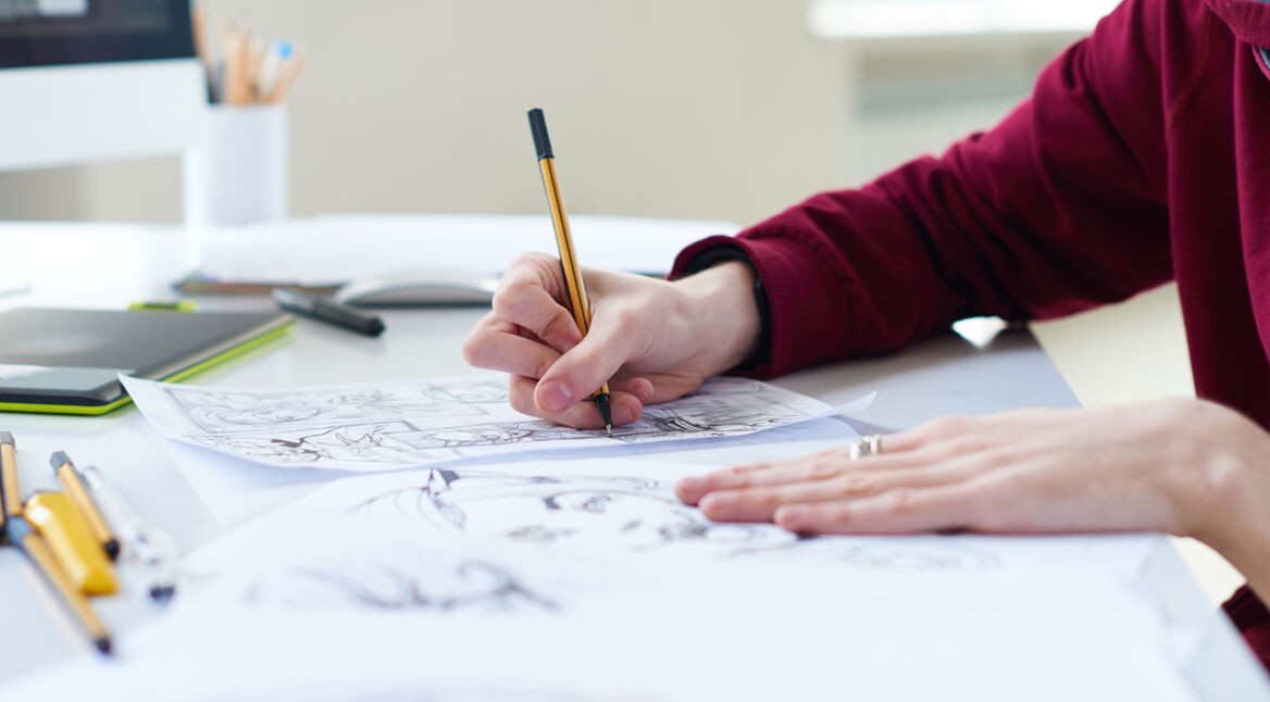 Ein Comic-Zeichner malt Linien auf seinem Bild nach,