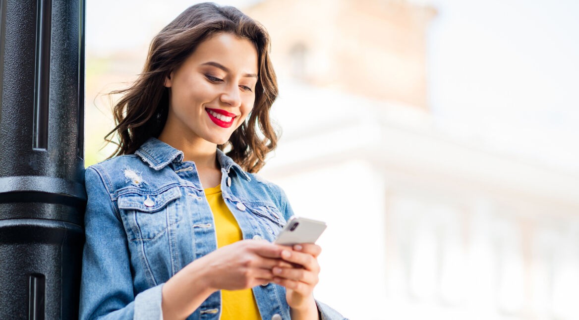 Frau mit Smartphone an Laterne