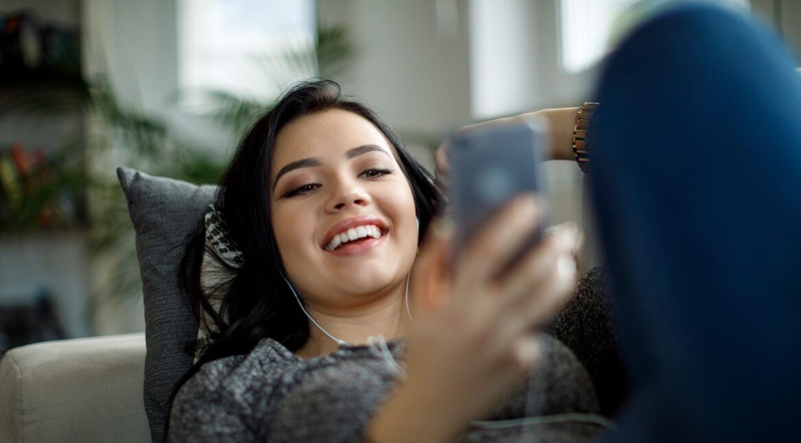 Frau streamt am Smartphone Musik mit Spotify.