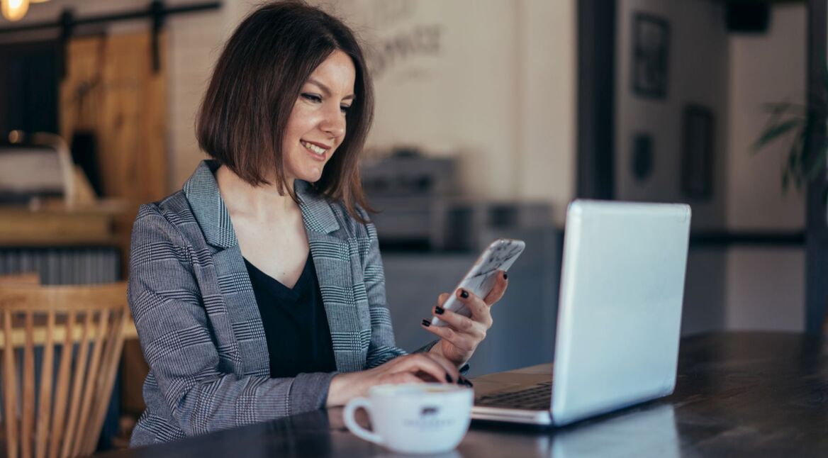 Frau nutzt Smartphone und Laptop.