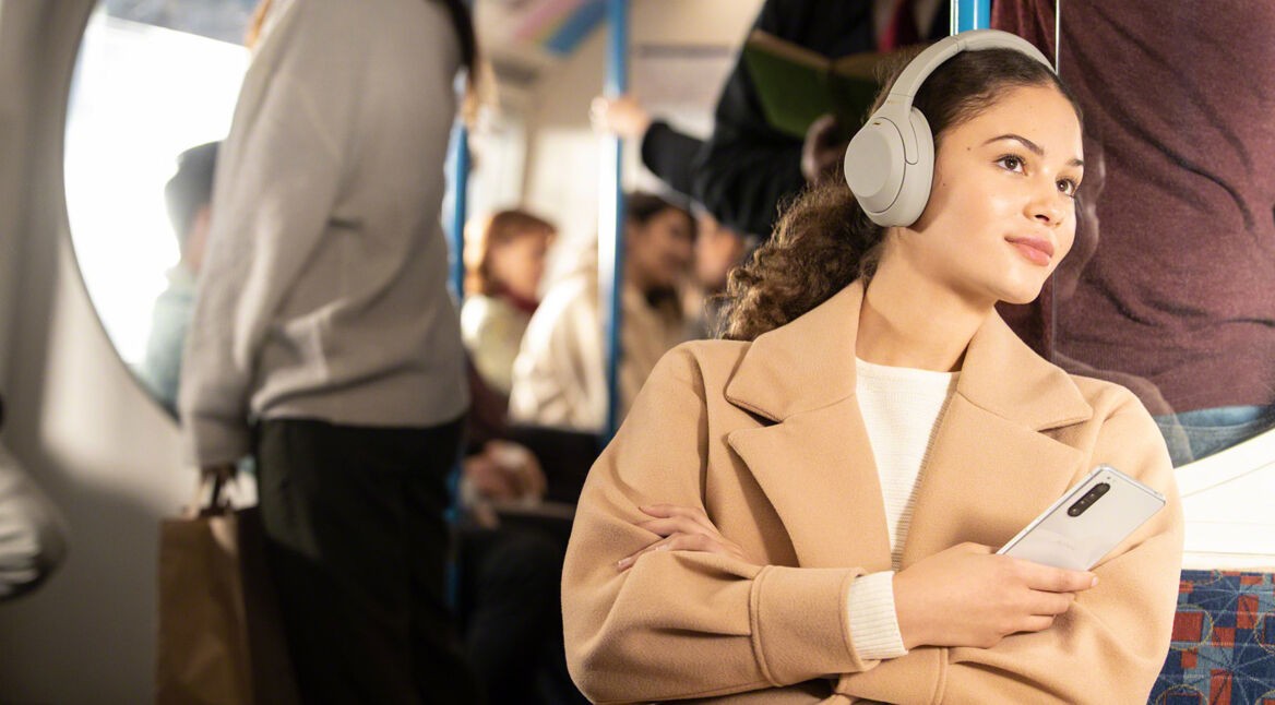 Frau nutzt Sony WH-1000XM4 in der Bahn
