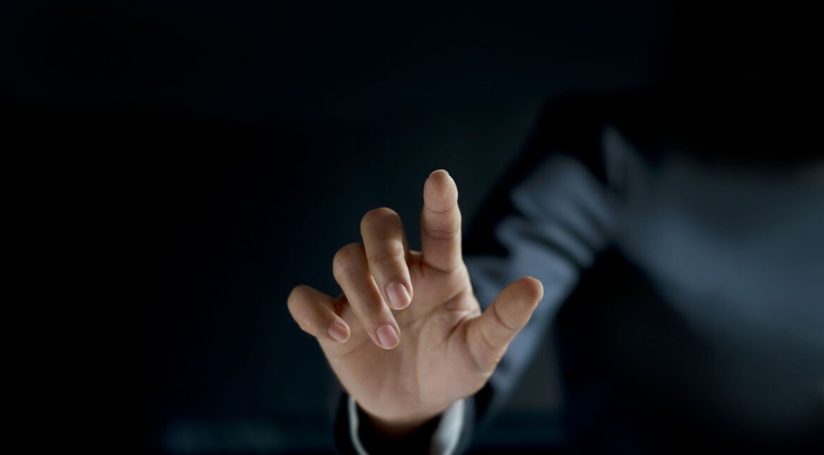 Eine Hand ragt aus der Dunkelheit in Richtung des Betrachters.
