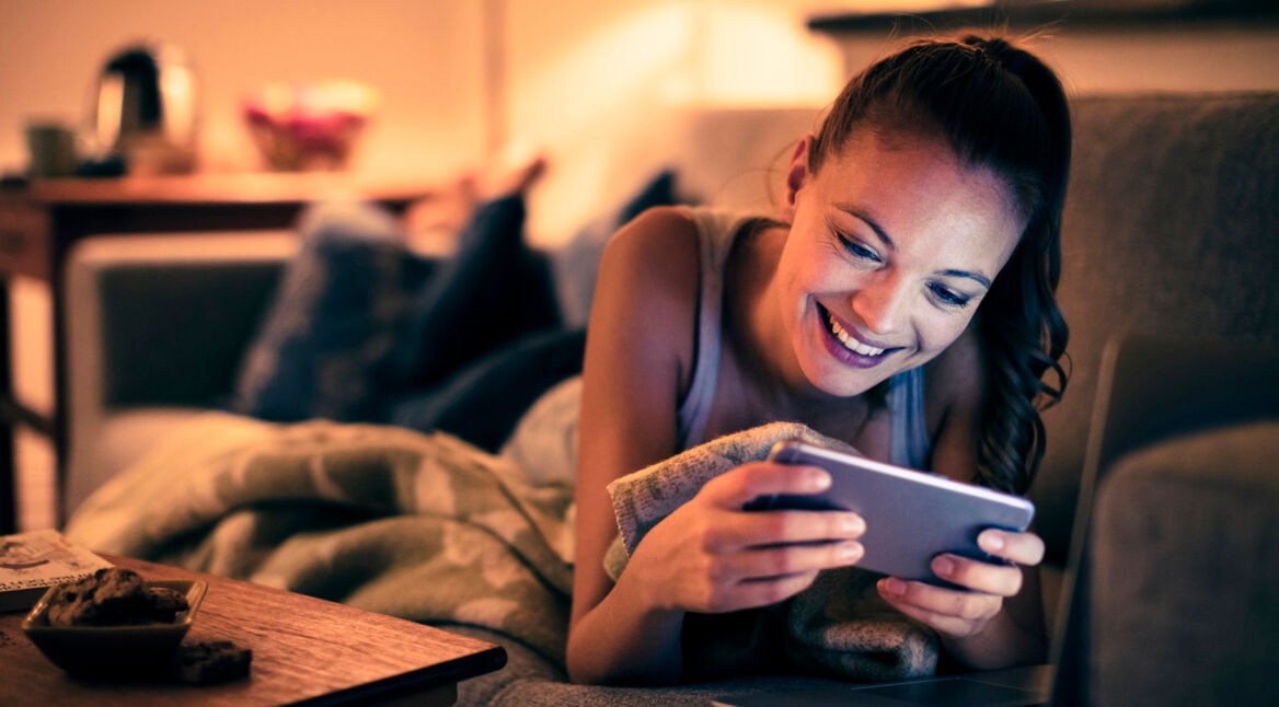 Frau mit iPhone im Landscape-Modus auf der Couch