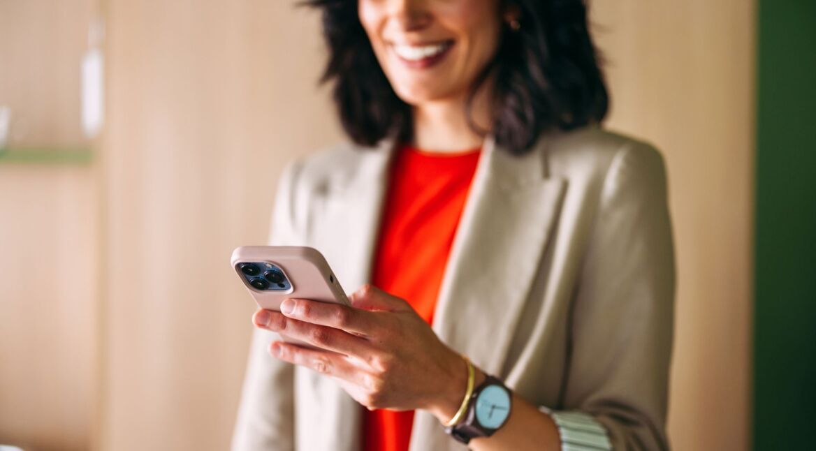 Eine Frau im Office-Look interagiert mit einem iPhone.