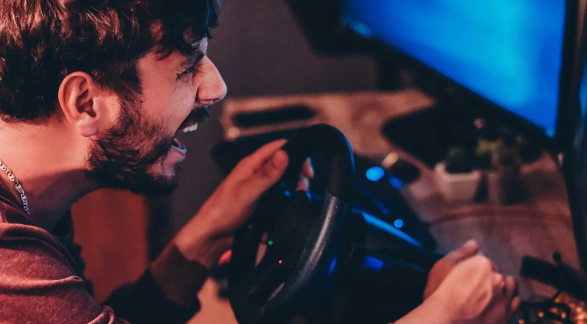 Mann spielt am Lenkrad ein Rennspiel