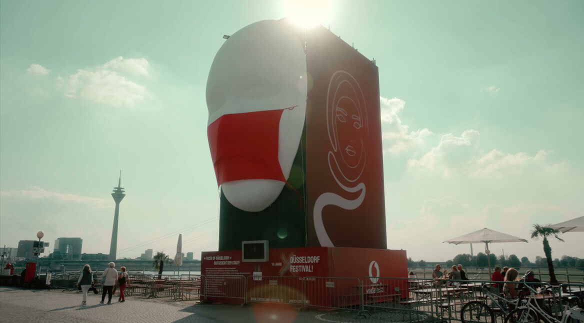 Die Kunst-Installation "Faces of Düsseldorf" von Jan Ising beim Düsseldorf Festival. Zu sehen ist ein Gesicht mit roter Corona-Maske, an der Seite LED-Animationen.