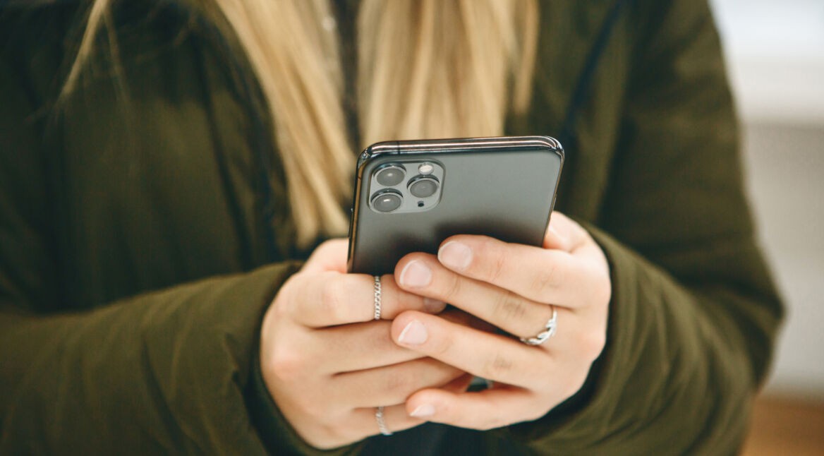 Frau hält ein iPhone in den Händen.