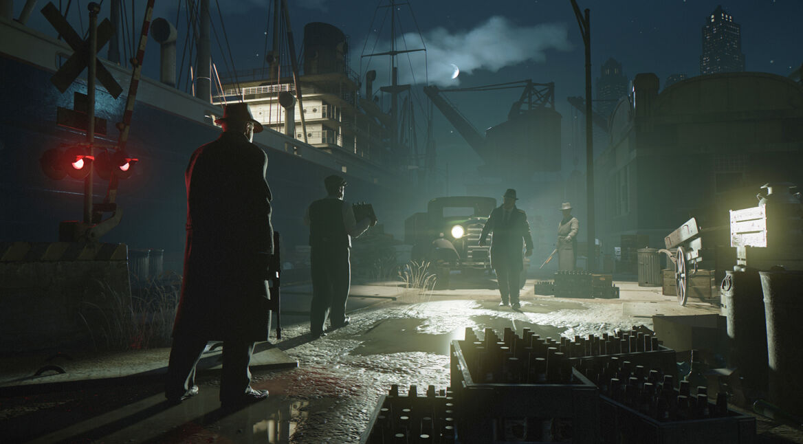 Artwork zum Remake der "Mafia: Definitiv Edition". Vier Personen stehen bei Nacht auf einem Hafengelände, eine trägt eine Waffe.