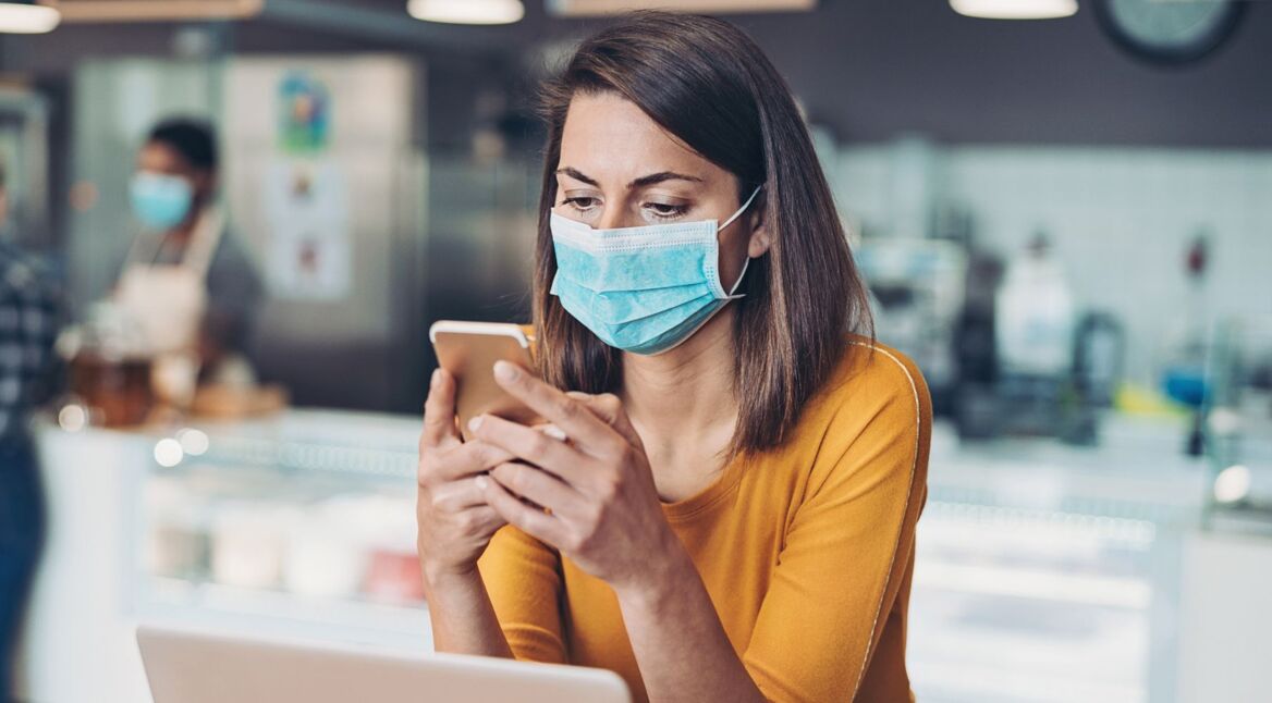 Frau sieht am Smartphone die Corona-Karte von Google ein