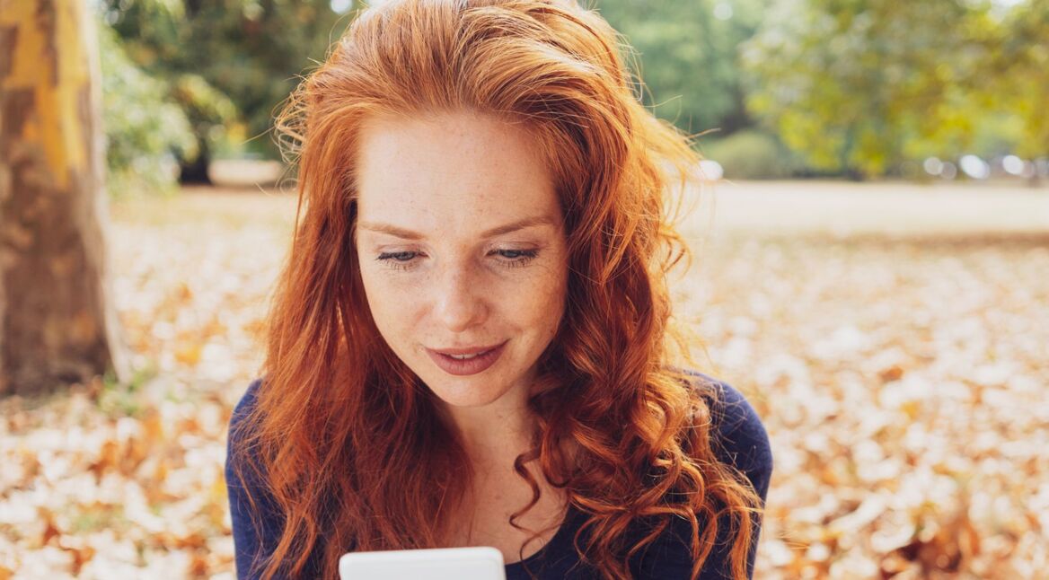 Junge Frau schaut auf ihr iPhone.