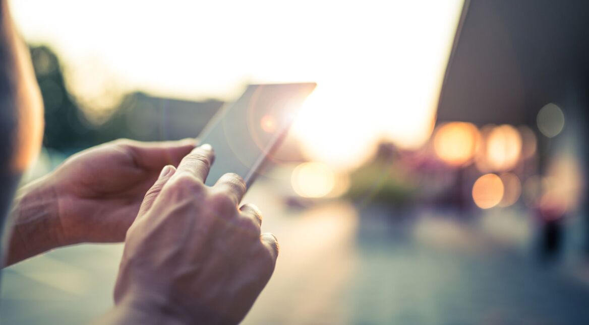 Mann hält Smartphone in der Hand.
