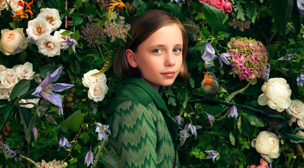Das Mädchen Mary (Dixie Egerickx) vor einer Blumenhecke im Film "Der geheime Garten".
