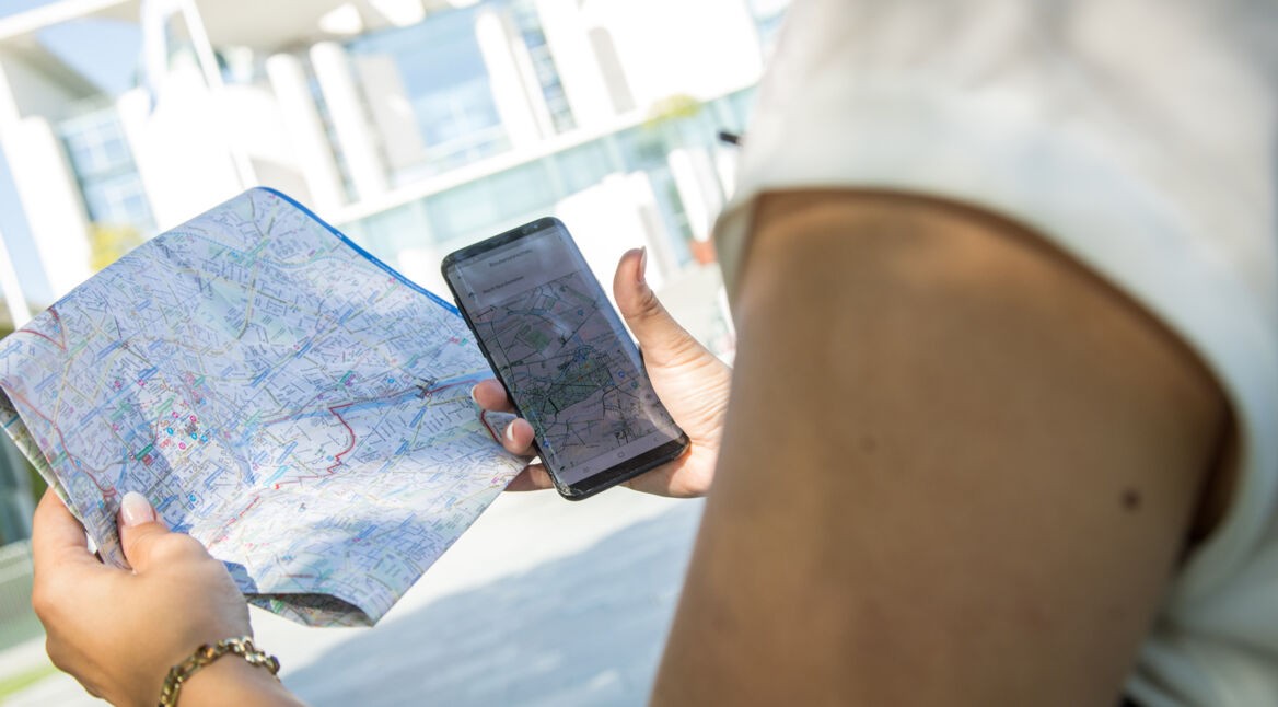 Frau hält Smartphone und Karte