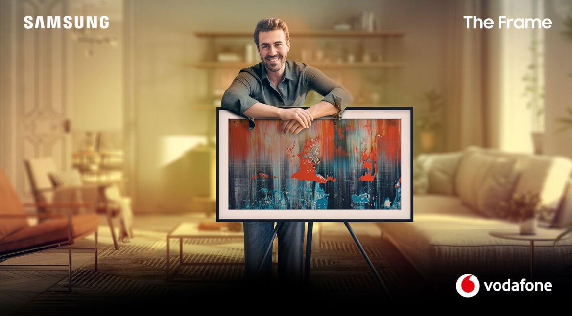 Ein Mann lehnt über seinem Fernseher, den Samsung "The Frame", der ein Kunstwerk zeigt.