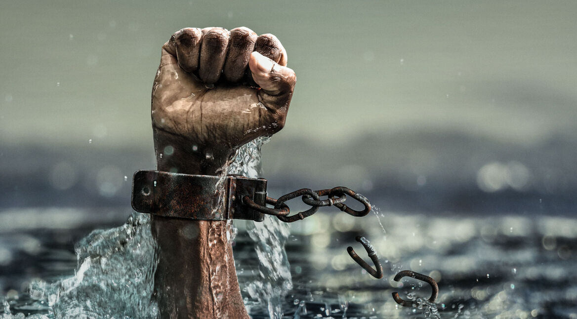 Die Faust einer Person, deren Handgelenk in Ketten liegt, stößt aus dem Meereswasser, symbolisch für die "Black Lives Matter"-Bewegung-