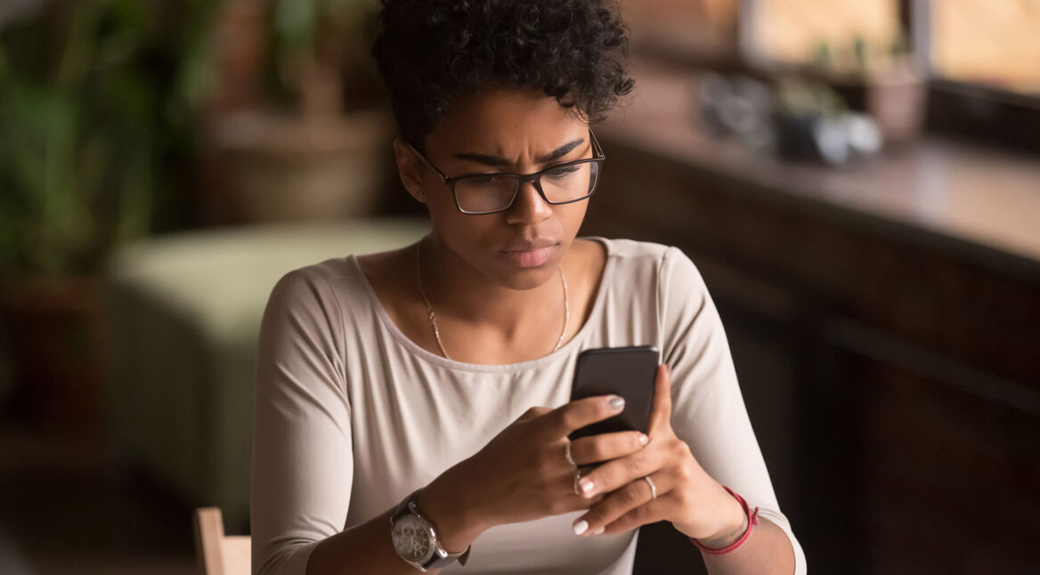 Frau schaut irritiert aufs Smartphone