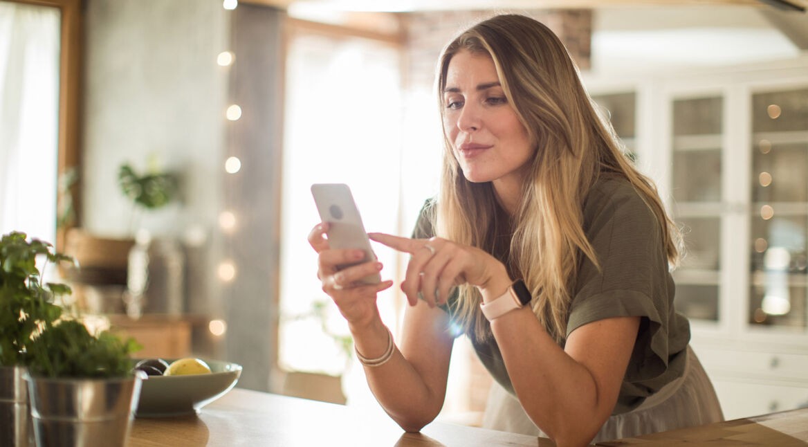 Frau nutzt Smartphone in der Küche