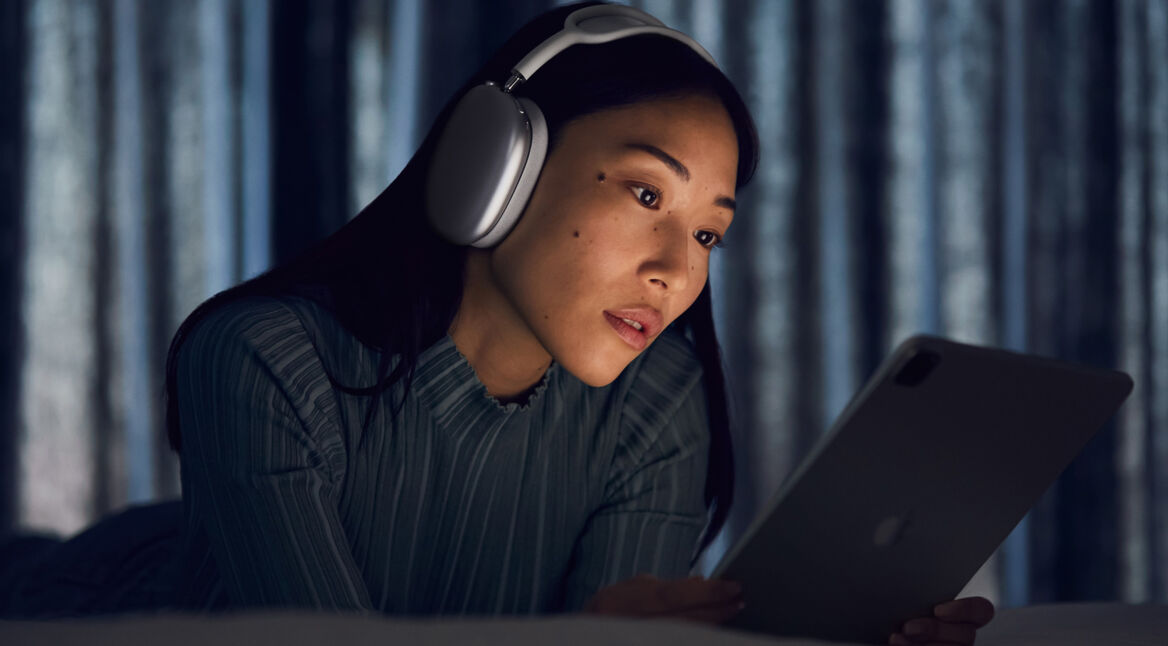 Frau trägt AirPods Max und guckt auf ihr iPad