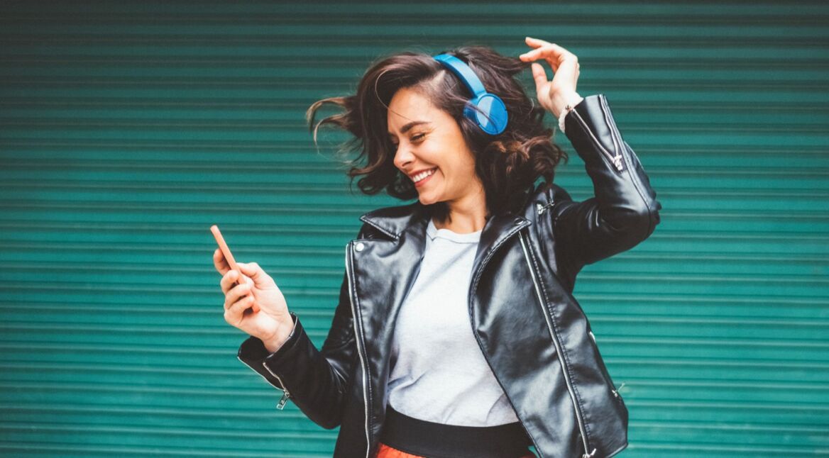 Frau auf grünem Hintergrund hört Musik.