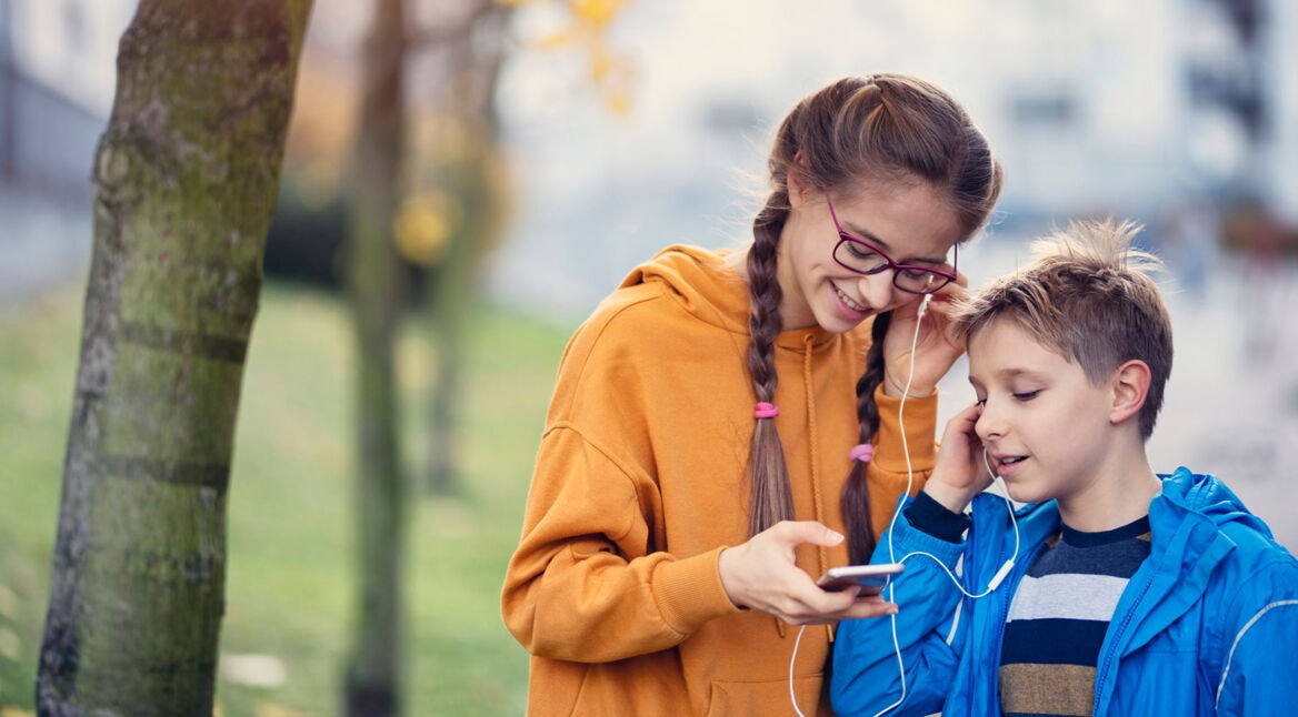 Bruder und Schwester hören Spotify Family auf dem Smartphone