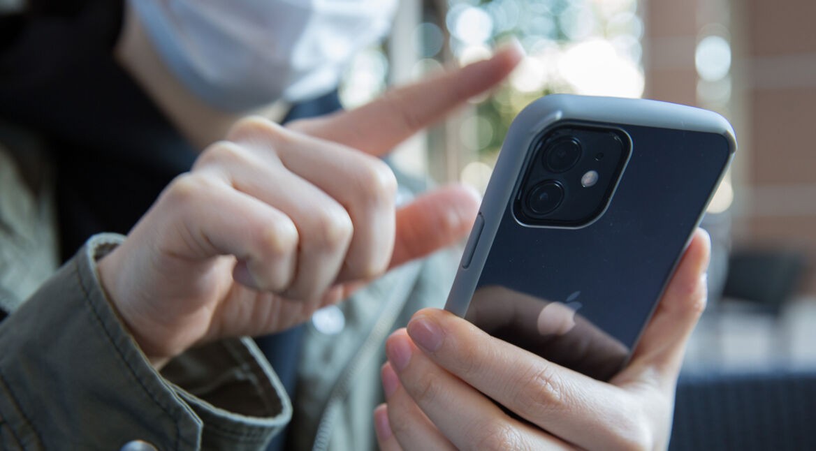 Frau wischt mit Finger auf iPhone 12