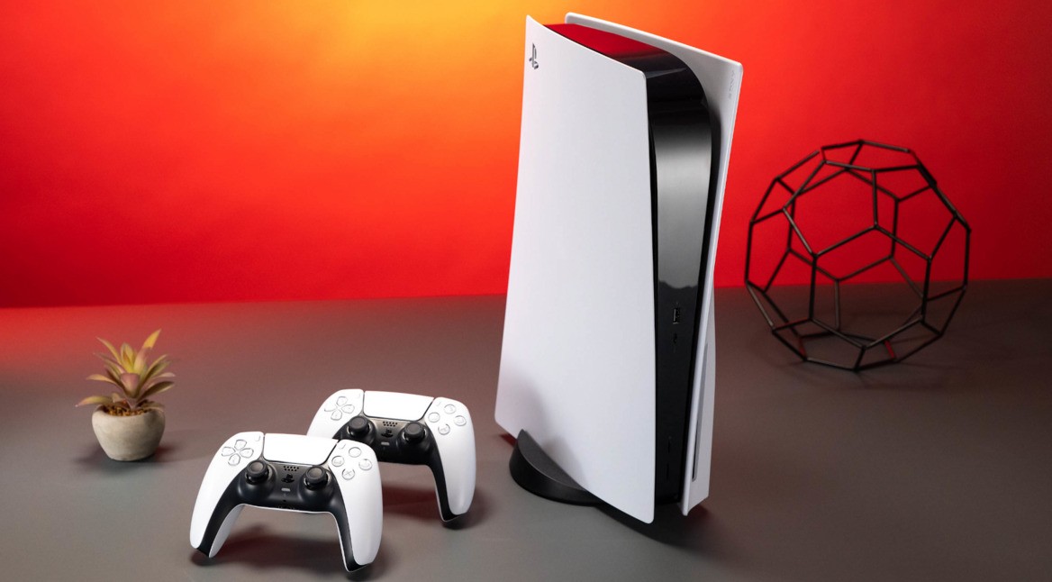 PlayStation 5 und Controller auf einem Tisch vor rotem Hintergrund