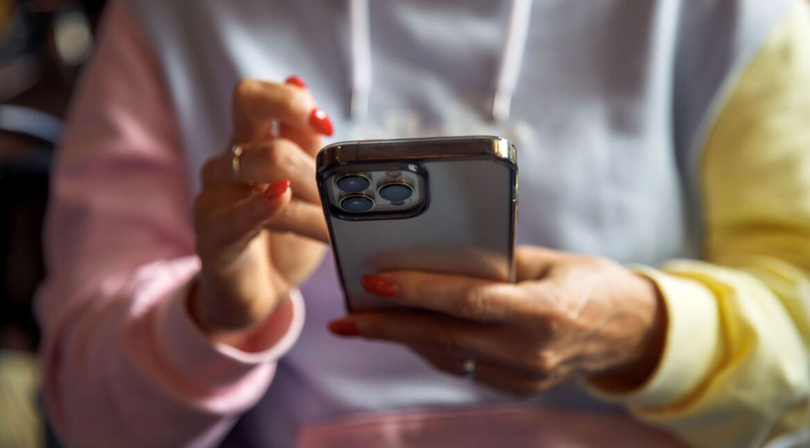Junge Frau tippt auf ihr iPhone.