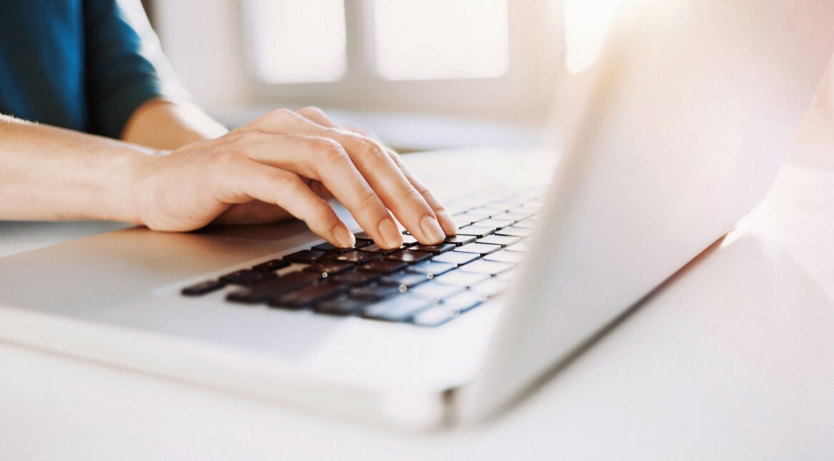 Frau tippt am Laptop