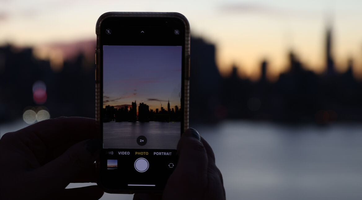 Smartphone fotografiert Skyline von New York im Sonnenuntergang