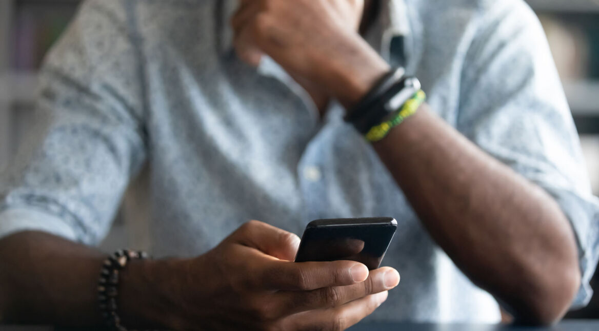 Grübelnder Mann hält Smartphone in der Hand
