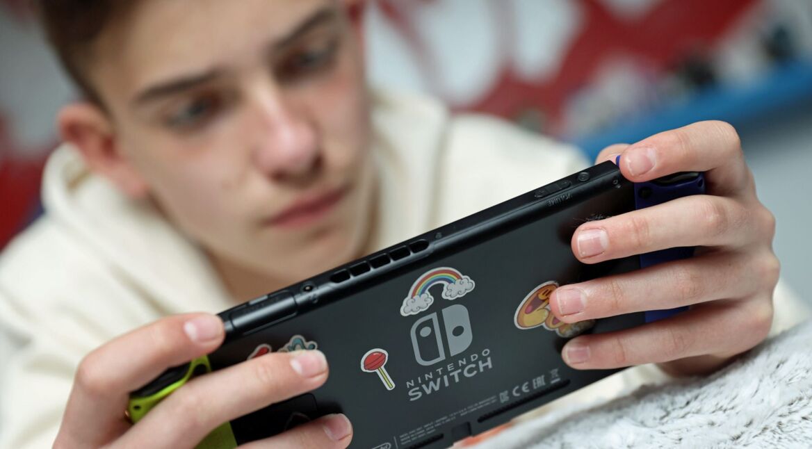 Junger Mann zockt Spiel an der Nintendo Switch.