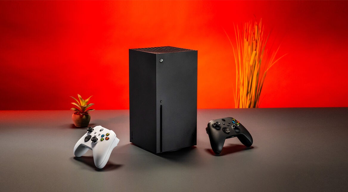 Zwei Xbox-Controller und eine Xbox Series X vor rotem Hintergrund