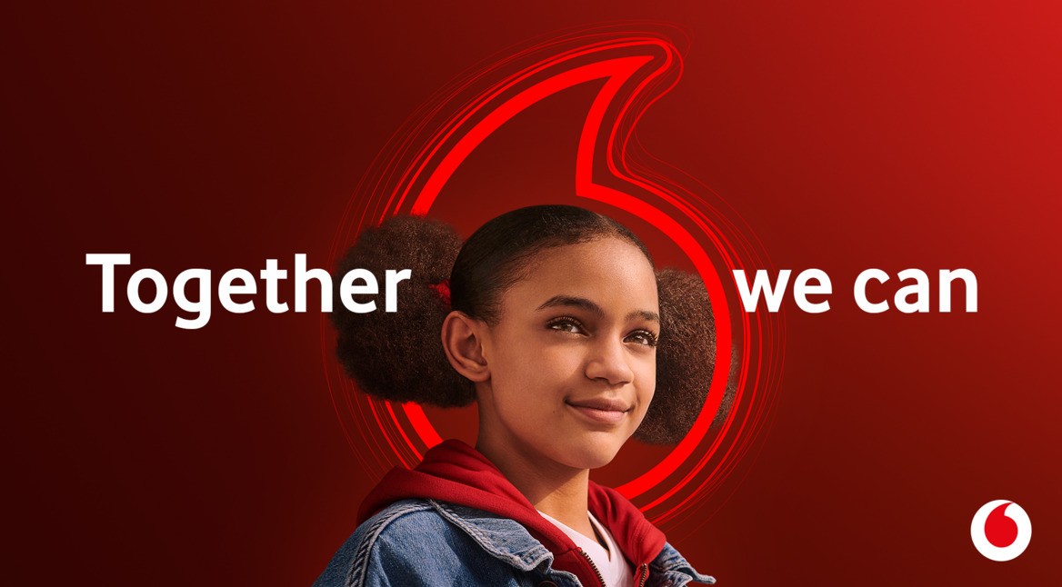 Ein Mädchen lächelt, umgeben ist sie vom Vodafone Speechmark und dem Claim "Together we can".