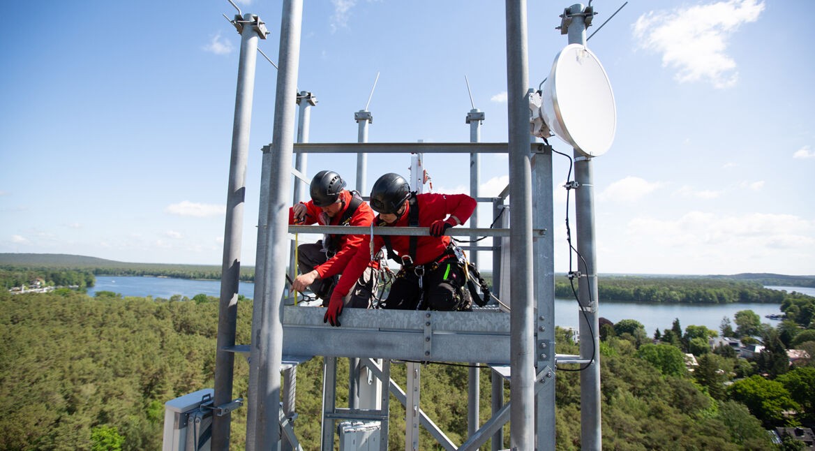 Vodafone-Techniker:innen montieren 5G-Antennen auf einer Mobilfunk-Station in Berlin.