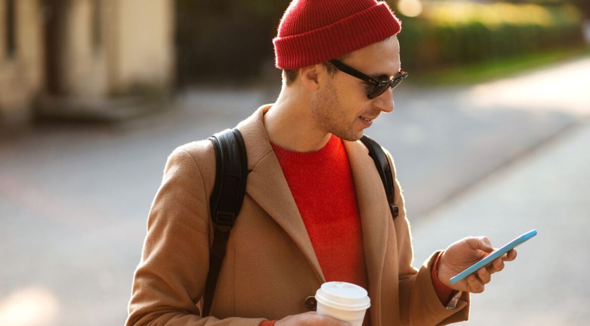 Mann schaut auf Smartphone in der Hand.
