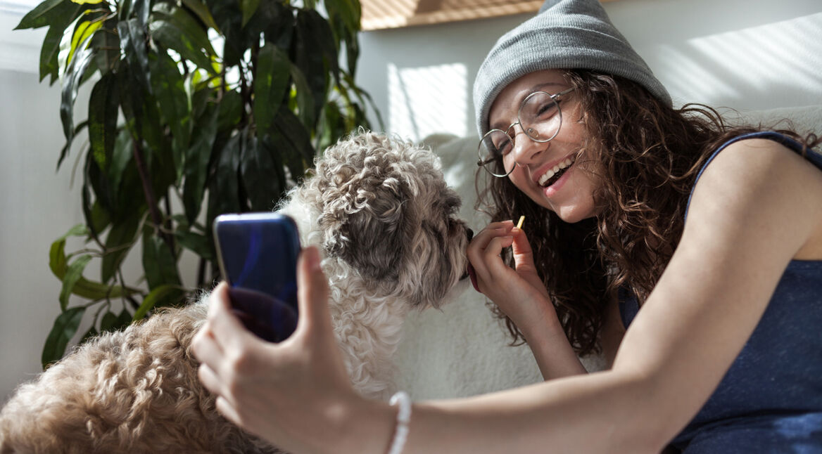 Eine Frau macht ein Foto von sich und ihrem Hund per Smartphone.